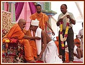 Swamishri imparting the Diksha mantra to the newly initiated parshad, while his father waits to garland Swamishri