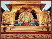 Swamishri seated on a resplendent stage, serenely chanting the holy name of Swaminarayan