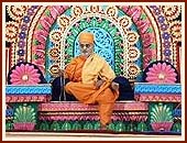 Swamishri seated on a colorful giant stage, serenely chanting the holy name of Swaminarayan