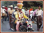 A motorcycle driver balances 8 pots on his head 