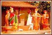 A colorful rustic stage depicting the celebration of Pushpadolotsav by Lord Swaminarayan with the paramhansas in the darbar of Rathod Dhadhal in Sarangpur    