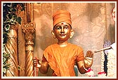 The murti of Harikrishna Maharaj is adorned in chandan as a sadhu with a rosary, pillow and potlu(bag)