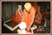 Swamishri places a garland and a kanthi on the murtis of Shastriji Maharaj and Yogiji Maharaj
