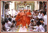 Swamishri is given a glorious and jubiliant welcome as he walks through Ambli Vali Pol*. The devotees joyously shower flowers and chorus thunderous 'Jays' in honor of Swamishri. * A cluster of adjoining homes with a narrow gully and a single entrance door