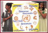 BAPS volunteers with a multi-language banner of Welcome for the international delegates