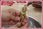 Lord Harikrishna Maharaj being bathed in warm water