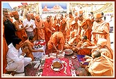 Swamishri splits a coconut on the sacred bricks
