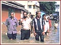 Volunteers wade through knee-high flood waters to help the needy