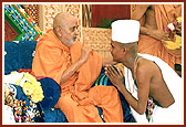Swamishri initiates a youth into parshad diksha and imparts the diksha mantra
