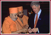 President Clinton listens keenly as Pramukh Swami Maharaj demonstrates how the rosary is chanted
