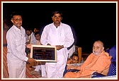 As part of the dedication ceremony, Swamishri offers a plaque to leading members of each village school