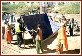 Volunteers and sadhus erecting a tent... 