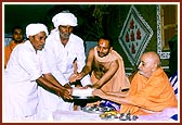 Swamishri presents the foundation bricks to leaders of the villages