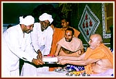 Swamishri presents the foundation bricks to leaders of the villages