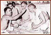The priest conducting the pratishtha ceremony performs pujan of Swamishri. To his right is P. Sant Swami and 