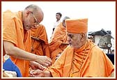 P. Ishwarcharan Swami ties the nada-chhadi on Swamishri's wrist