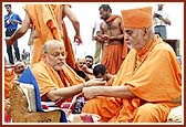 Swamishri ties nada-chhadi and applies chandlo to  P. Ishwarcharan Swami