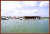 Sadhus and devotees are engaged in darshan of the rituals from the river bank 