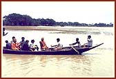 Sadhus and volunteers cross flooded areas by boat and on foot to deliver relief supplies to flood victims