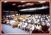 Swamishri and guests view a visual presentation in the Institute's auditorium