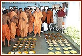 Swamishri showers flower petals over Annakut items