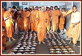 Swamishri showers flower petals over Annakut items