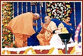 Pujya Doctor Swami offers a bouquet and pranams