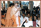 Swamishri adorned with a garland of 'mamra' (puffed rice grains) hand-scripted devotionally with the 'Swaminarayan' mahamantra by devotees of Khandesh
