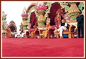 Chief Minister, Shri Narendrabhai Modi, on stage listening to a summary of the BAPS Swaminarayan Sanstha's Earthquake Rehabilitation Work