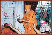 Swamishri showers flower petal on the murtis as a part of the Vedic ceremony