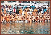 Senior sadhus seated on the river bank as Swamishri bathes Harikrishna Maharaj