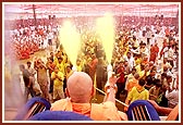 Swamishri profusely blesses the devotees by spraying colored water as they pass by