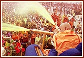 Swamishri sprays the holy colored water on the ecstatic devotees