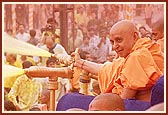 Swamishri profusely blesses the devotees by spraying colored water as they pass by