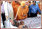 Swamishri is apprised of Shrujan Singh's condition, the NSG commando injured during Operation Thundernight, by the doctors and blesses him and prays for his recovery. Swamishri gently blesses him with the touch of his hand and showers sacred rose petals