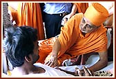 Swamishri holds Harikrishna Maharaj before each of the injured, blesses them by gently placing his hand on them and encourages them with words for their quick recovery