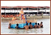 Swamishri is brought to the middle of the river standing on a decorated raft.