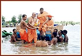 Swamishri enters the river and prepares to take a holy dip.