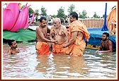 Swamishri enters the river and prepares to take a holy dip.