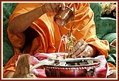   Swamishri ceremoniously bathes Shri Harikrishna Maharaj with panchamrut during the rituals
