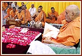 While sadhus sing bhajans, Swamishri chants the holy name of Swaminarayan in his puja