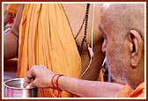 Swamishri sanctifies water with relics of Shriji Maharaj and Gurus