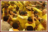 Devotees euphorically raise their hands holding plastic bags and bottles to collect and be blessed with the holy, colored water