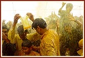 Devotees euphorically raise their hands holding plastic bags and bottles to collect and be blessed with the holy, colored water