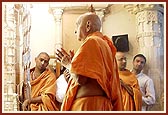 Swamishri with folded hands before the murtis of Dharmakul in the last shrine