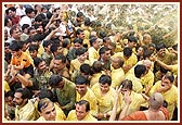 Devotees ecstatically raise their hands and dance to be blessed with the shower of holy, colored water