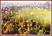 Devotees ecstatically raise their hands and dance to be blessed with the shower of holy, colored water