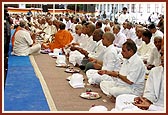 Sadhaks engaged in the parshad diksha rituals, with their parents besides them