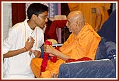 A kishore from the UK welcomes Swamishri with a garland