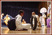 A blind-folded kishore is guided by Swamishri through an obstacle course